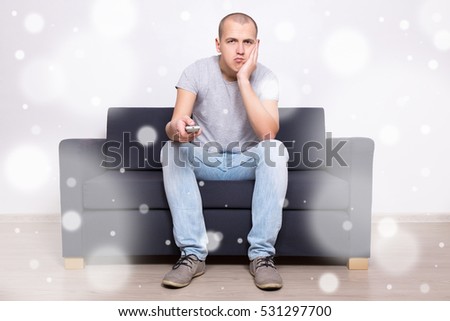 stock-photo-young-bored-man-sitting-on-sofa-and-watching-tv-at-home-531297700.jpg