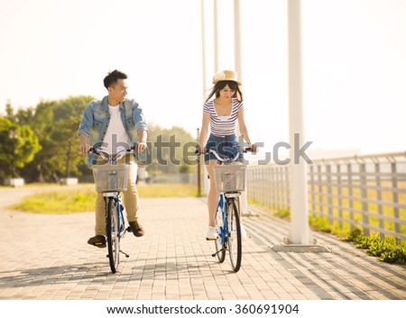 happy young couple riding on bicycle in city park
