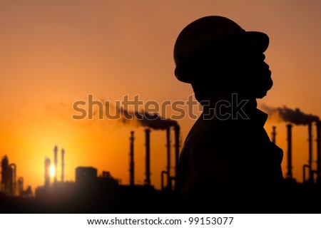 The silhouette of oil refinery worker at sunset