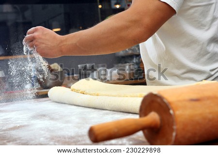 Baker poured flour on the table for rolling dough