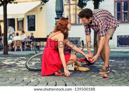 man fell down from the bicycle and woman help him to collect products