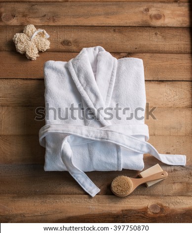 bathrobe bath soap and loofah brush behind wooden table