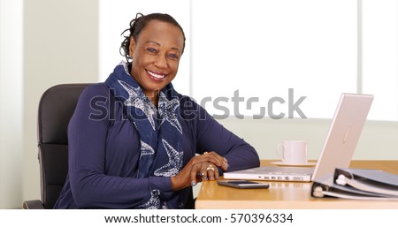A black businesswoman poses for a portrait at her desk