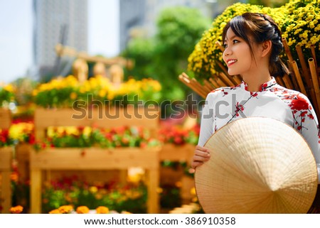 Traditional Clothing Of Vietnam, Asia. Beautiful Happy Asian Girl Dressed In National Traditional Ao Dai Dress ( Costume ), Vietnamese Conical Hat ( Non La, Leaf Hat ) In Flower Garden. Culture.