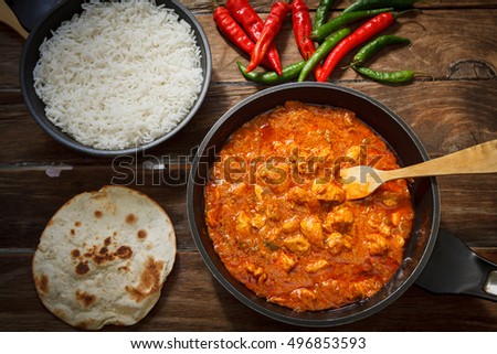 butter chicken curry on pot with green and red chili pepper