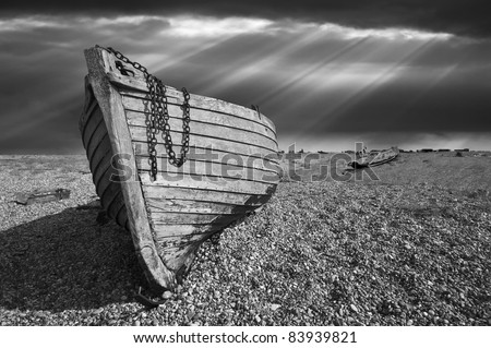 Black and white image of an old wooden fishing boat left to rot and decay on Black and white image of an old wooden fishing boat left to rot and decay on