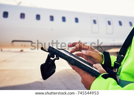 Modern technology at the airport. Member of the ground staff preparing the passenger airplane before flight.