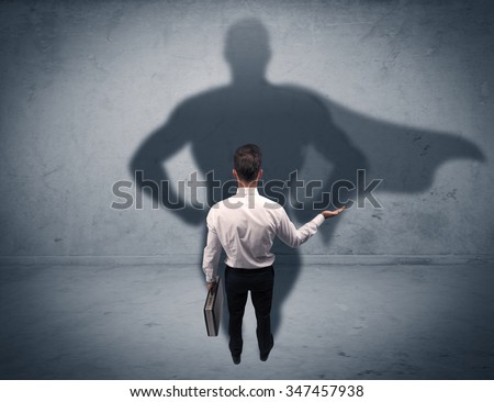 A confident young elegant salesman with briefcase facing a wall, looking at his superman shadow concept