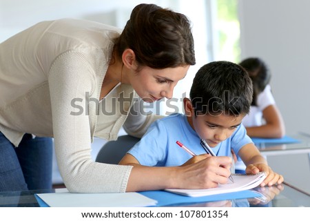 Teacher helping young boy with writing lesson