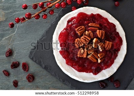 Brie topped with cranberries and pecans, above view on slate background
