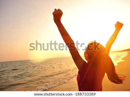 cheering woman open arms to sunrise at sea 