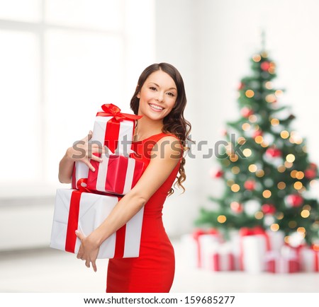 christmas, x-mas, valentine's day, celebration concept - smiling woman in red dress with many gift boxes