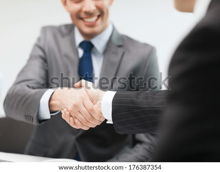 businesss and office concept - two businessmen shaking hands in office