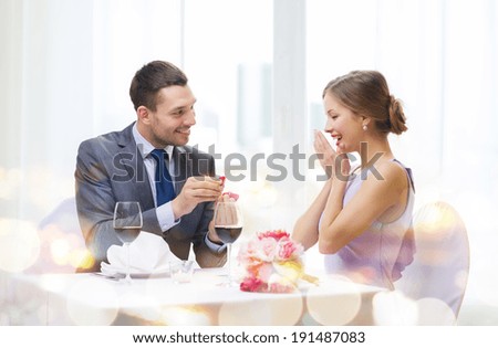 restaurant, couple and holiday concept - smiling man proposing to his girlfriend at restaurant