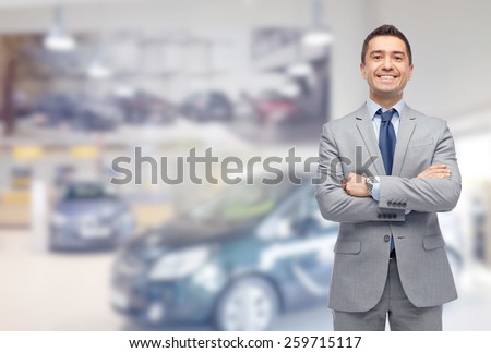 business, car sale, consumerism and people concept - happy man over auto show or salon background