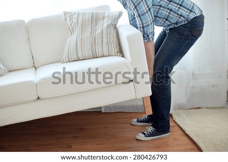 new home, real estate, moving and furniture concept - close up of male lifting up sofa or couch