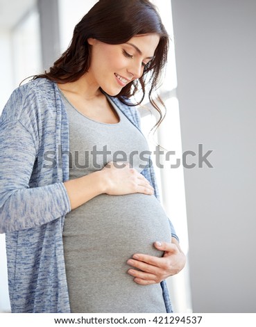 pregnancy, motherhood, people and expectation concept - happy pregnant woman with big tummy at home