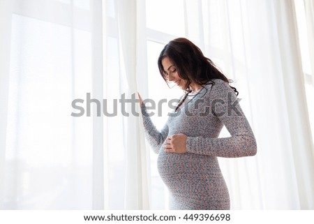 pregnancy, motherhood, people and expectation concept - close up of happy pregnant woman with big belly at window