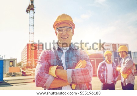 business, building, teamwork and people concept - group of smiling builders in hardhats at construction site