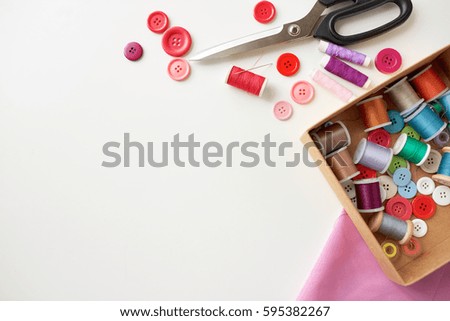 needlework, craft, sewing and tailoring concept - box with thread spools and buttons on table