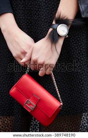 MILAN - FEBRUARY 25: Woman poses for photographers with red Fendi bag and black fur watch before Fendi fashion show, Milan Fashion Week Day 2 street style on February 25, 2016 in Milan.