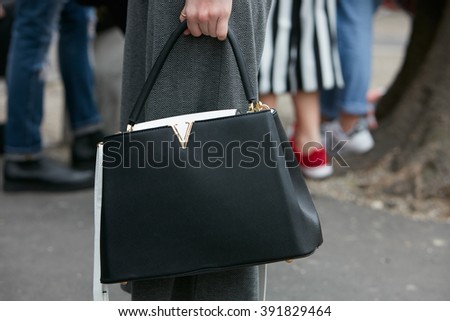 MILAN - FEBRUARY 26: Woman poses for photographers with black and white Louis Vuitton bag before Emporio Armani fashion show, Milan Fashion Week Day 3 street style on February 26, 2016 in Milan.