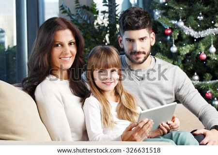 https://thumb1.shutterstock.com/display_pic_with_logo/665353/326631518/stock-photo-portrait-of-smiling-woman-and-his-husband-with-their-cute-daughter-sitting-at-living-room-next-to-326631518.jpg