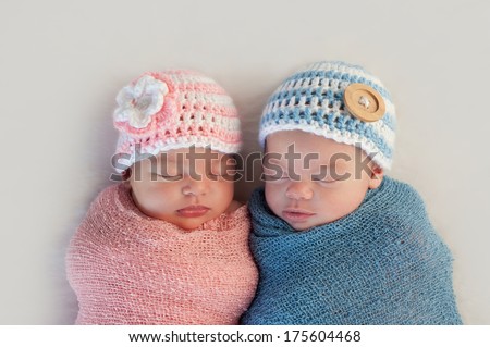 Five week old sleeping boy and girl fraternal twin newborn babies. They are wearing crocheted