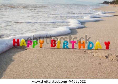 Happy birthday candles on a beach. - stock photo