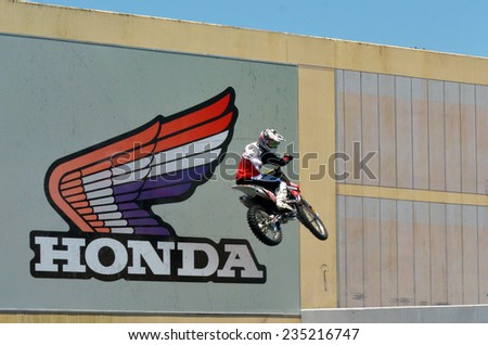 GOLD COAST, AUS - NOV 06 2014:Biker jumps beside Honda Motor billboard.Honda has been the world's largest motorcycle manufacturer since 1959