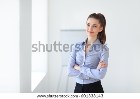 Portrait of young beautiful business woman in the office. Crossed arms