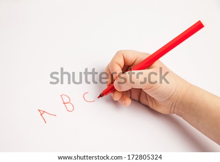 Hand of a child writing letters on white paper