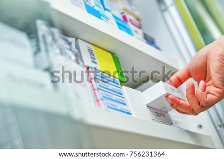 Closeup pharmacist hand holding medicine box in pharmacy drugstore.