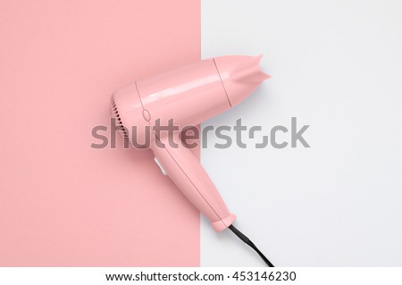 Pink hair dryer on pink and white paper background