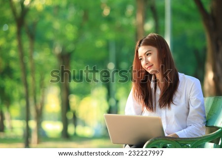 beautiful asian woman using laptop computer in the park