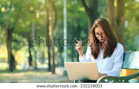 beautiful asian woman using laptop computer in the park