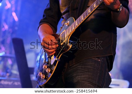artist Guitarist hand play electricity guitar on concert stage with blue light, Practicing in playing . song entertainment and music instrument.