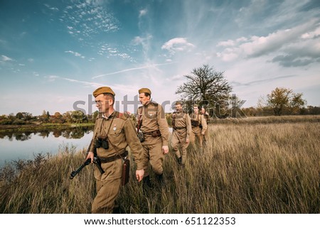 Dyatlovichi, Belarus - October 1, 2016: Group Of Reenactors Men Dressed As Russian Soviet Red Army Infantry Soldiers Of World War II Marching In Autumn Field With Weapons At Historical Reenactment
