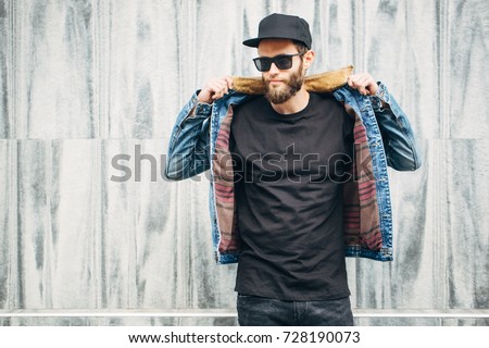 Hipster handsome male model with beard wearing black blank t-shirt with space for your logo or design in casual urban style