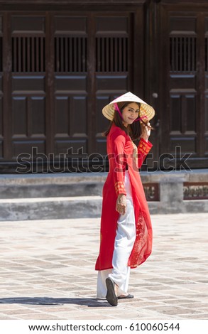 a woman in red ao dai Vietnamese's traditional costumes walking in the ancient city