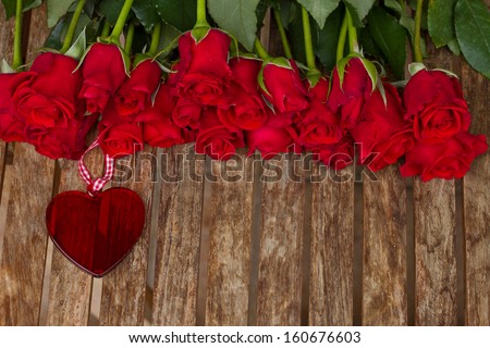 row of roses with red heart on wooden table