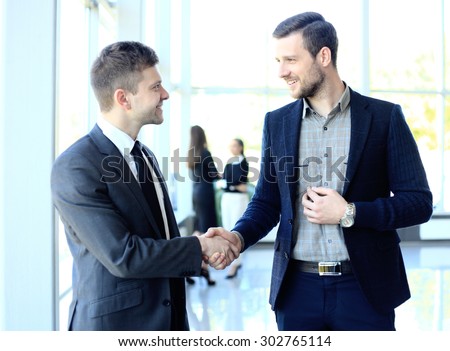businesss and office concept - two businessmen shaking hands in office
