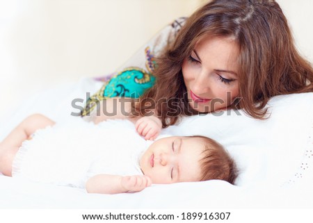 happy young mother near sleeping baby girl