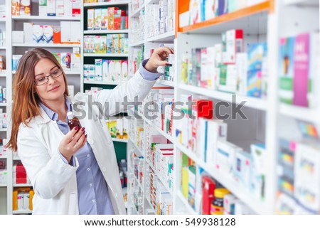 Woman pharmacist holding prescription checking medicine in pharmacy (or drugstore