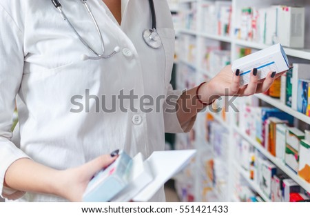 Woman pharmacist holding prescription checking medicine in pharmacy - drugstore.