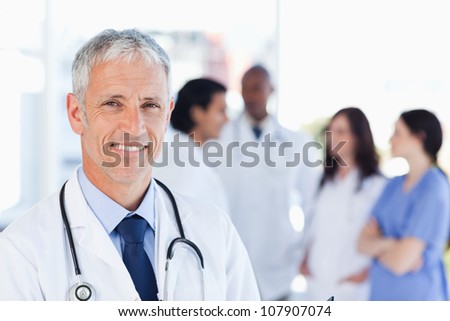 Smiling doctor waiting for his team while standing upright