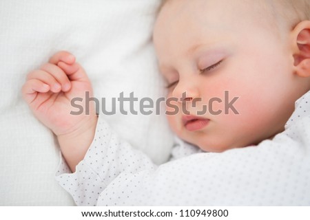 Peaceful baby lying on a bed while sleeping in a bright room