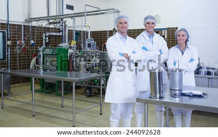 Biologist team with arms crossed smiling at camera in the factory