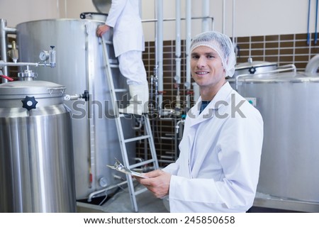 Scientist holding a clipboard and smiling at the camera in the factory