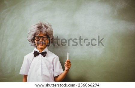 Portrait of little boy dressed as senior teacher in front of blackboard